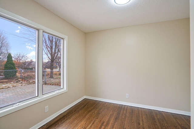 spare room featuring dark hardwood / wood-style flooring and a textured ceiling