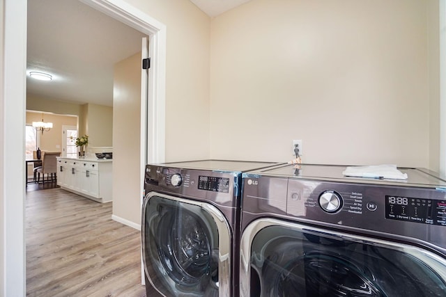 laundry area featuring light hardwood / wood-style floors, a notable chandelier, and independent washer and dryer