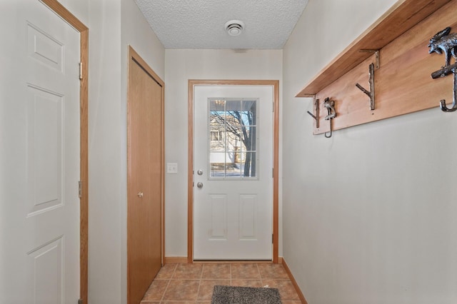 entryway featuring light tile patterned floors and a textured ceiling