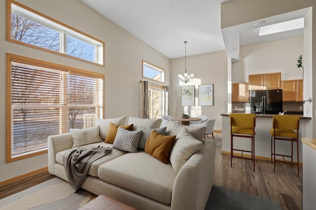 living room with a high ceiling, dark hardwood / wood-style flooring, and an inviting chandelier