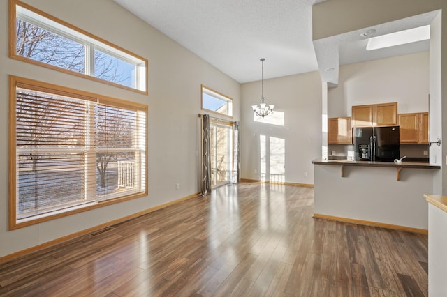 interior space featuring dark hardwood / wood-style floors, a towering ceiling, a textured ceiling, and a chandelier