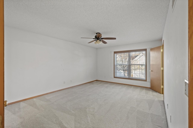 empty room with light carpet, ceiling fan, and a textured ceiling