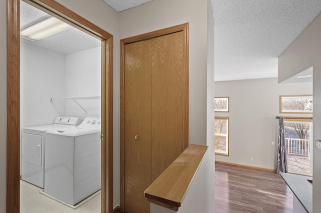 laundry area with light hardwood / wood-style floors, independent washer and dryer, and a textured ceiling