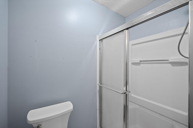 bathroom featuring walk in shower, a textured ceiling, and toilet