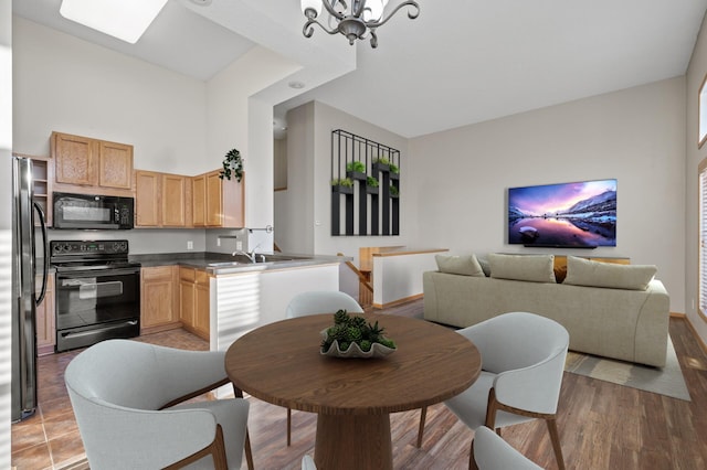 kitchen with light wood-type flooring, sink, black appliances, light brown cabinets, and an inviting chandelier