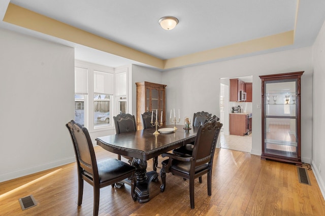 dining space with light wood-type flooring, baseboards, and visible vents