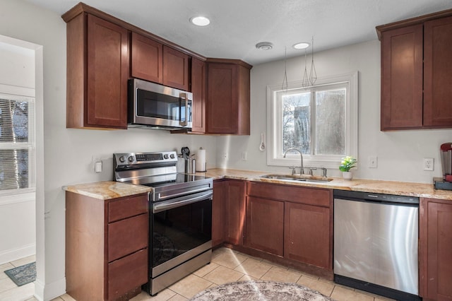 kitchen with light tile patterned floors, recessed lighting, appliances with stainless steel finishes, a sink, and light stone countertops