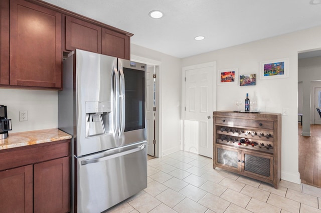 kitchen featuring light stone counters, light tile patterned floors, recessed lighting, stainless steel fridge with ice dispenser, and baseboards