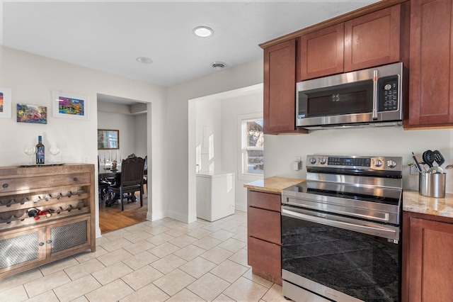 kitchen featuring baseboards, light stone counters, brown cabinets, stainless steel appliances, and light tile patterned flooring