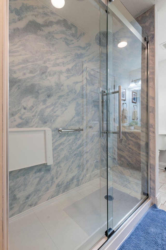 bathroom with tile patterned flooring, visible vents, and a marble finish shower