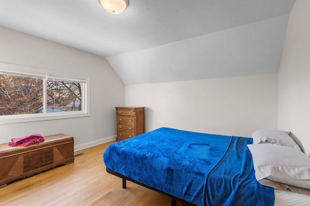 bedroom with vaulted ceiling, baseboards, and wood finished floors