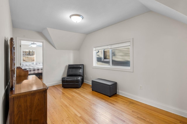 living area with lofted ceiling, baseboards, and light wood finished floors