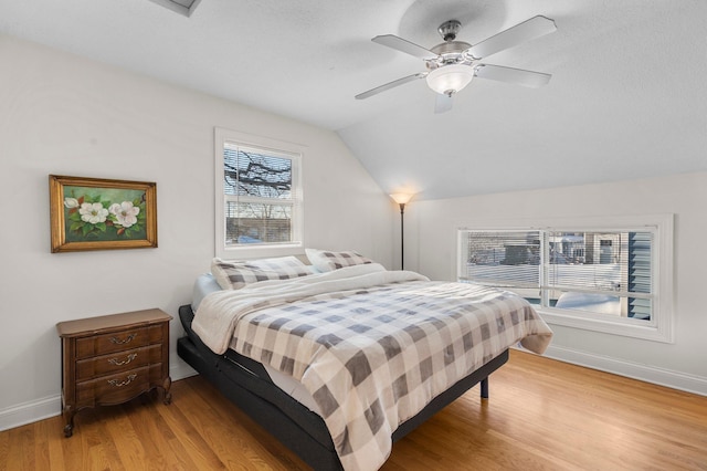 bedroom with vaulted ceiling, ceiling fan, baseboards, and light wood-style floors