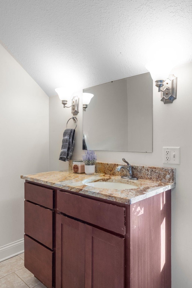 bathroom with vanity, baseboards, a textured ceiling, and tile patterned floors