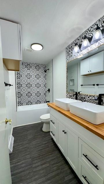 full bathroom with tiled shower / bath combo, toilet, wood-type flooring, and vanity