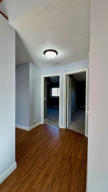 hall featuring a textured ceiling and dark hardwood / wood-style floors