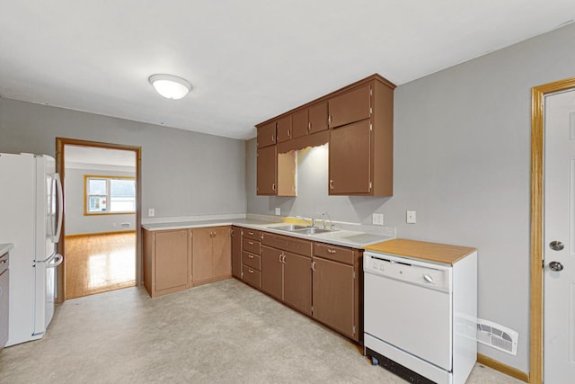 kitchen with white appliances, light colored carpet, and sink