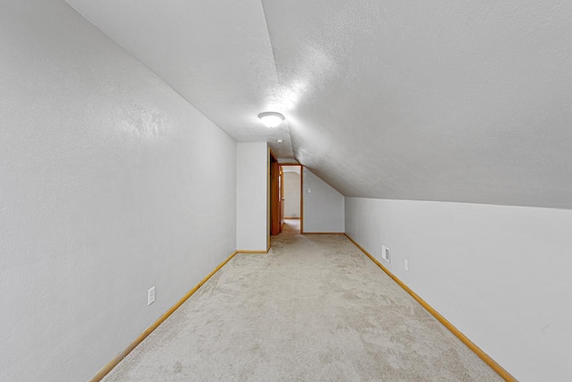 bonus room with a textured ceiling, light carpet, and vaulted ceiling