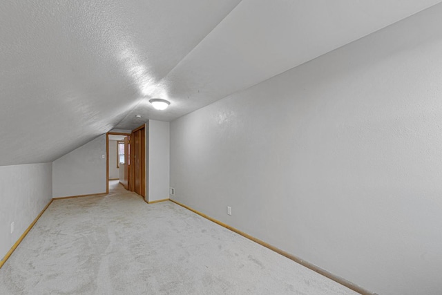 bonus room featuring light colored carpet, lofted ceiling, and a textured ceiling