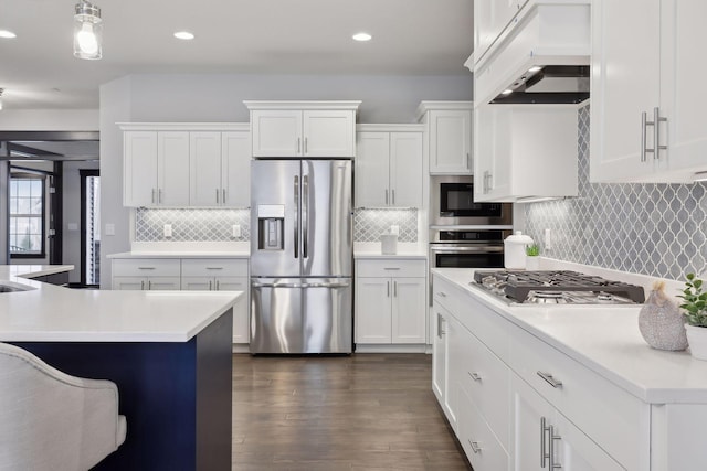 kitchen featuring white cabinets, dark hardwood / wood-style floors, appliances with stainless steel finishes, decorative light fixtures, and custom range hood