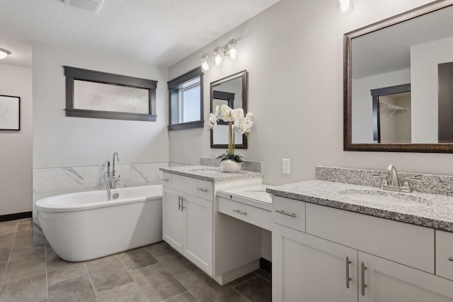 bathroom featuring vanity, a textured ceiling, a tub, and tile patterned flooring