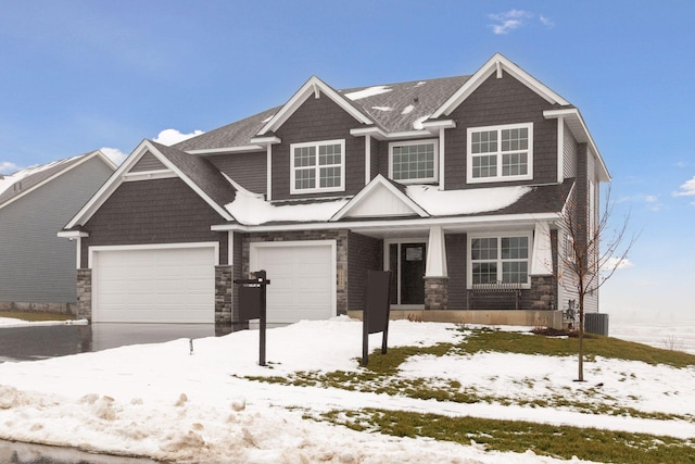 craftsman inspired home featuring a garage, stone siding, driveway, and central AC