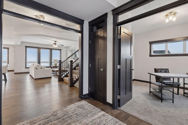 hall featuring dark wood-style floors, stairway, and baseboards