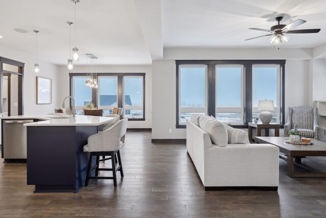 living area featuring visible vents, baseboards, dark wood-type flooring, and ceiling fan with notable chandelier