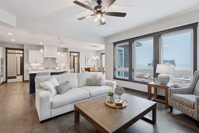 living area featuring baseboards, dark wood-type flooring, a ceiling fan, and recessed lighting