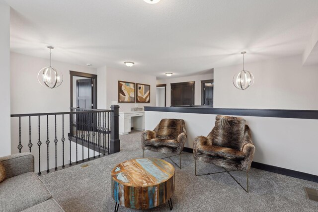 sitting room with baseboards, visible vents, an upstairs landing, carpet floors, and a chandelier