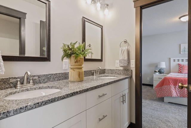 ensuite bathroom featuring baseboards, connected bathroom, a sink, and double vanity