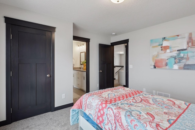 bedroom featuring visible vents, light carpet, connected bathroom, a textured ceiling, and baseboards