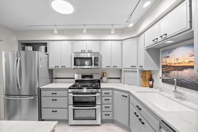 kitchen featuring light stone counters, sink, stainless steel appliances, and a textured ceiling