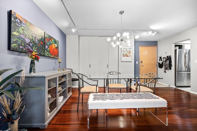 dining room with track lighting, dark hardwood / wood-style flooring, a textured ceiling, and a notable chandelier