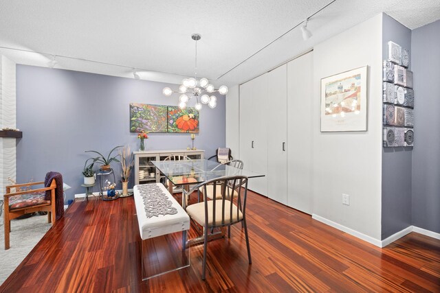 dining area with hardwood / wood-style flooring, track lighting, a textured ceiling, and a chandelier