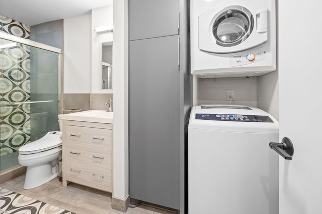 washroom with stacked washer and clothes dryer and sink