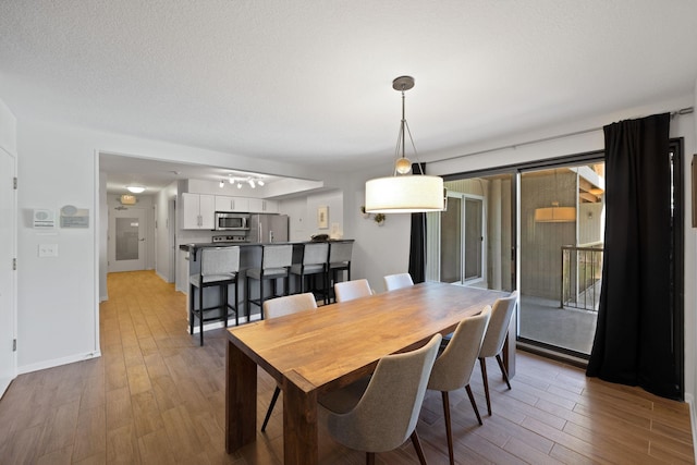 dining room with wood-type flooring and a textured ceiling