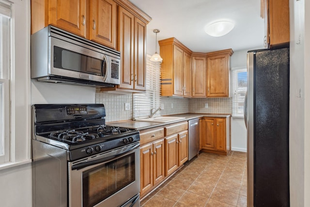 kitchen featuring light tile patterned flooring, appliances with stainless steel finishes, pendant lighting, tasteful backsplash, and sink