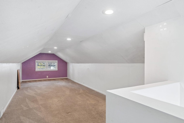 bonus room with vaulted ceiling and light colored carpet