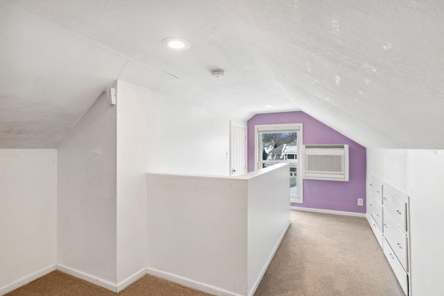 additional living space with light colored carpet, vaulted ceiling, and a textured ceiling