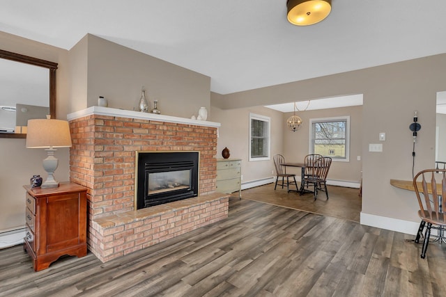 living room featuring dark hardwood / wood-style flooring, a notable chandelier, and a brick fireplace