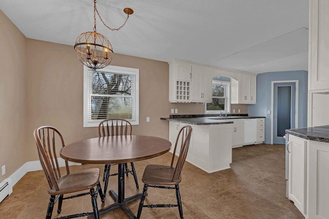 dining room with sink, a baseboard radiator, and an inviting chandelier