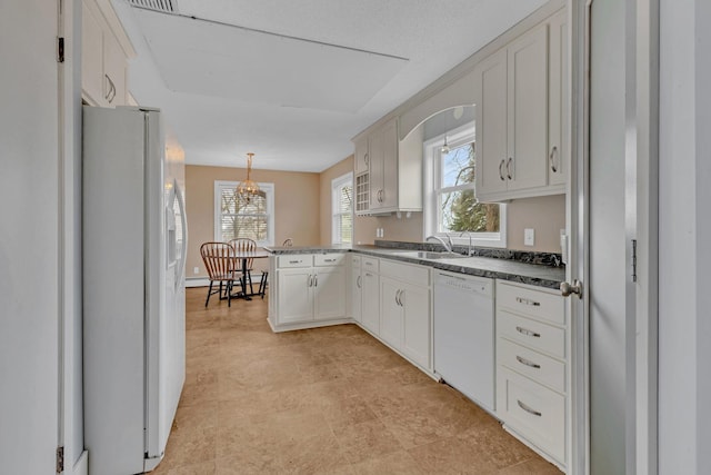 kitchen featuring a wealth of natural light, sink, pendant lighting, and white appliances