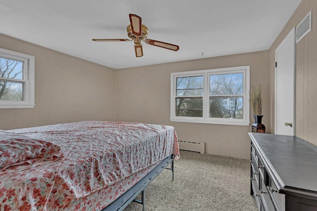 bedroom with multiple windows, ceiling fan, light colored carpet, and a baseboard radiator