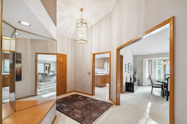 foyer featuring high vaulted ceiling, light colored carpet, and an inviting chandelier