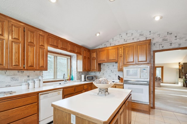 kitchen featuring lofted ceiling, white appliances, sink, light tile patterned floors, and a kitchen island