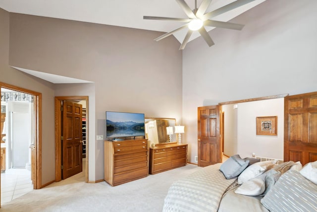 bedroom featuring ceiling fan, ensuite bathroom, light carpet, and high vaulted ceiling