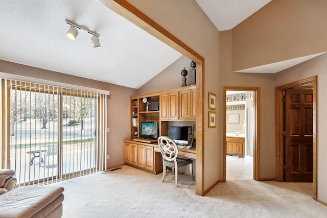 carpeted home office with a textured ceiling, track lighting, and vaulted ceiling