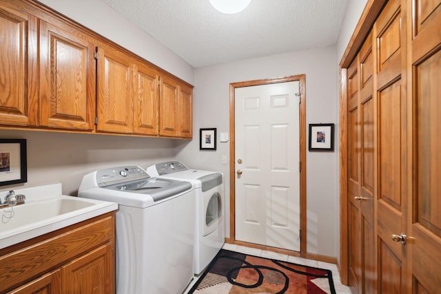 washroom featuring cabinets, a textured ceiling, sink, dark tile patterned flooring, and independent washer and dryer