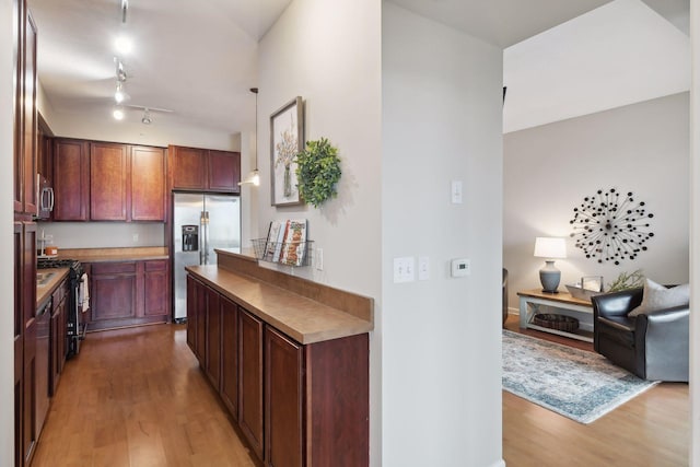 kitchen with pendant lighting, light hardwood / wood-style flooring, rail lighting, and stainless steel appliances